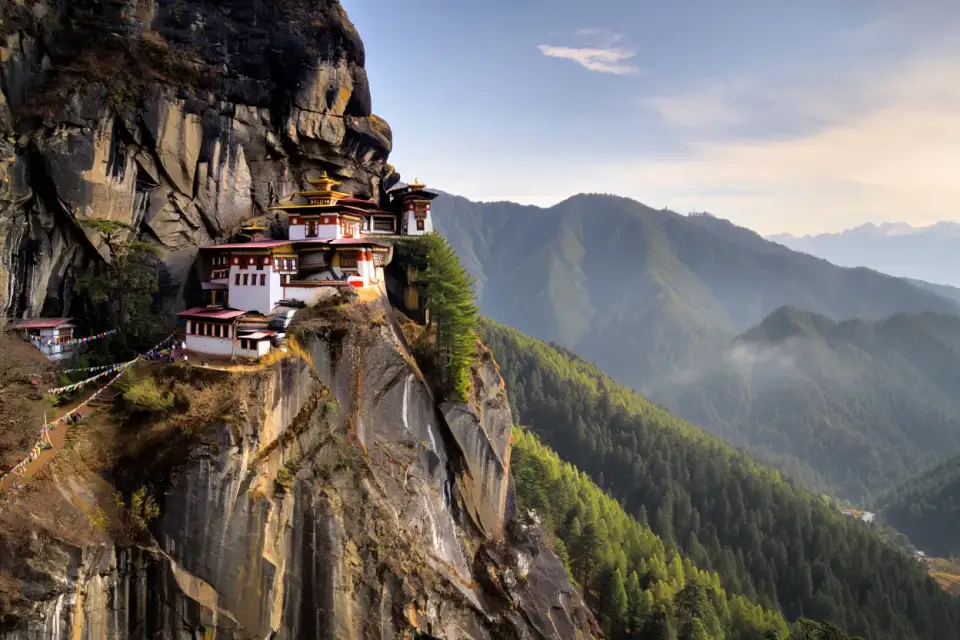Le monastère de la Tanière du Tigre (Taktshang) accroché à la falaise dans la vallée de Paro au Bhoutan, forêt de pins et montagnes himalayennes
