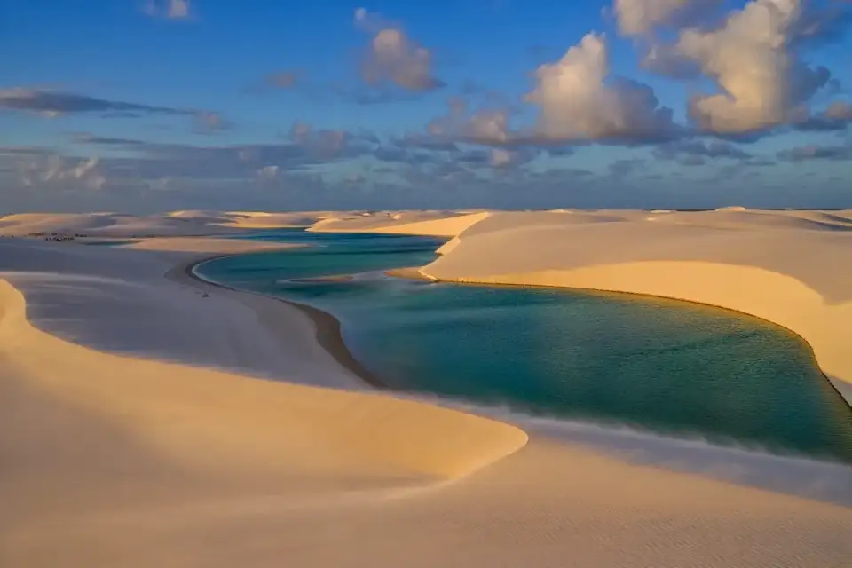 Dunes dorées et lagons turquoise des Lençóis Maranhenses dans le Nordeste brésilien, ciel dramatique à l'heure dorée