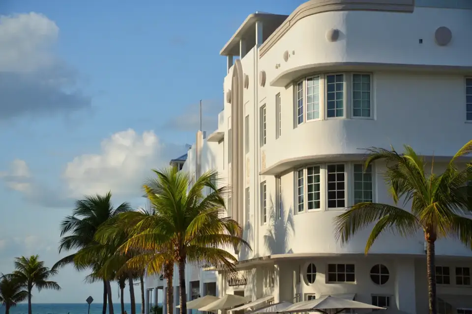 Façade Art déco blanche d'un hôtel de Miami Beach avec palmiers et ciel bleu, lumière dorée de fin d'après-midi