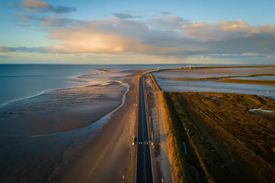 Le passage du Gois à marée basse reliant l'île de Noirmoutier au continent en Vendée, avec le ciel atlantique et les marais salants