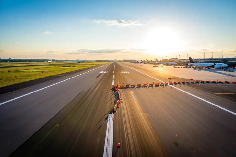 Vue aérienne de l'aéroport Paris-Orly avec pistes et terminaux, lumière dorée d'été, avions commerciaux au sol