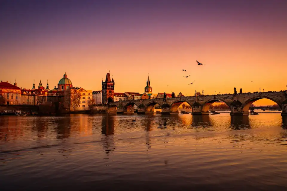 Vue panoramique du Pont Charles à Prague au coucher du soleil, tours baroques et reflets sur la Vltava