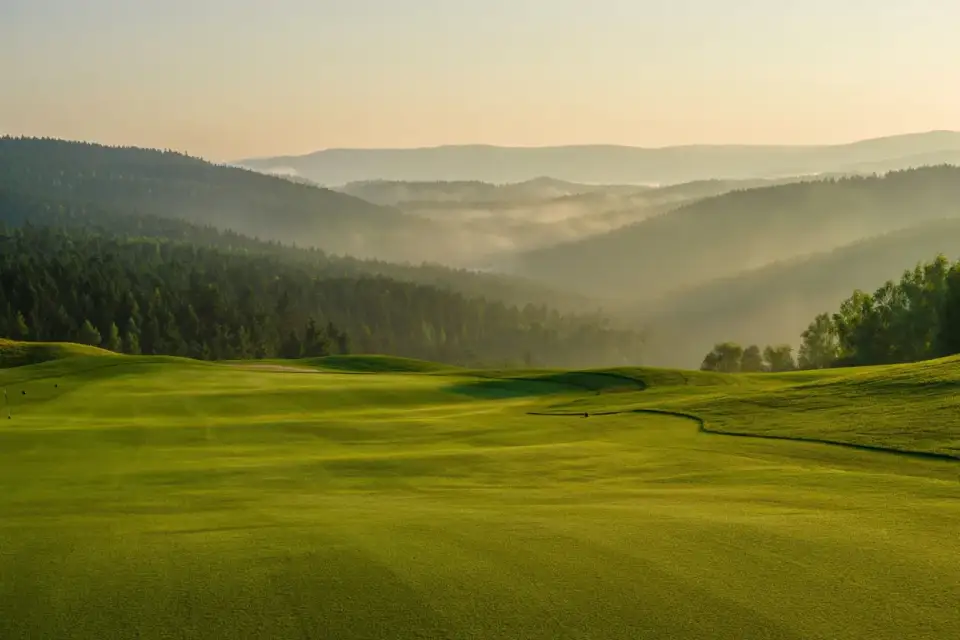 Parcours de golf dans les montagnes des Beskides en Moravie-Silésie, République tchèque, avec forêts de pins et collines verdoyantes sous une lumière dorée