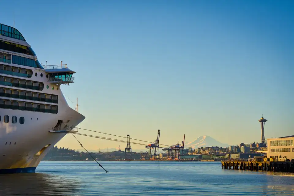 Port de Seattle avec navires de croisière amarrés à Elliott Bay, ciel dégagé sur fond de montagnes enneigées et grues portuaires